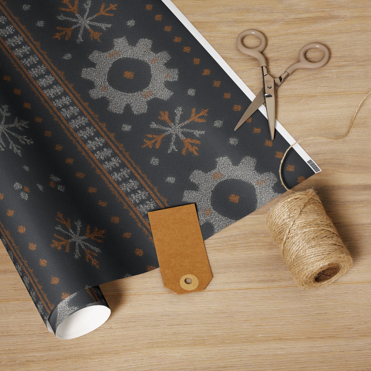 Roll of decorative paper with snowflake pattern, scissors, and twine on a wooden surface