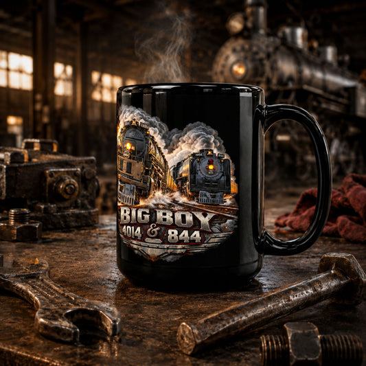 A black ceramic mug with a detailed graphic of two steam trains and the text 'BIG BOY 404 & 844', set on a rustic workbench with wrenches and tools in a steam workshop environment.