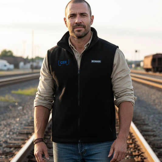 Man wearing a black vest with Columbia logo on train tracks