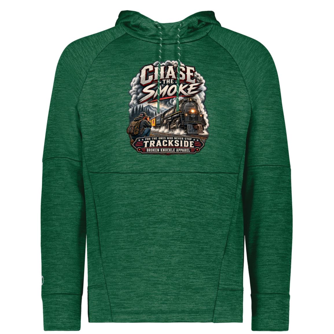 Green Holloway performance fleece hoody featuring a graphic of a photographer with a backpack kneeling trackside, taking a picture of a large steam locomotive rolling through a forest landscape. Bold distressed text reads "CHASE THE SMOKE" at the top and "FOR THE ONES WHO NEVER STOP TRACKSIDE" in a vintage banner at the bottom.