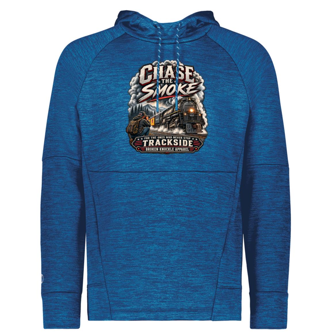 Royal Blue Holloway performance fleece hoody featuring a graphic of a photographer with a backpack kneeling trackside, taking a picture of a large steam locomotive rolling through a forest landscape. Bold distressed text reads "CHASE THE SMOKE" at the top and "FOR THE ONES WHO NEVER STOP TRACKSIDE" in a vintage banner at the bottom.