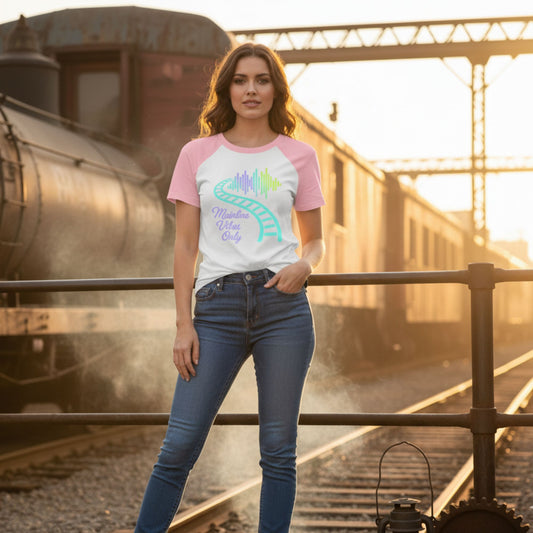 Woman wearing a colorful t-shirt and jeans standing on train tracks with a train in the background.