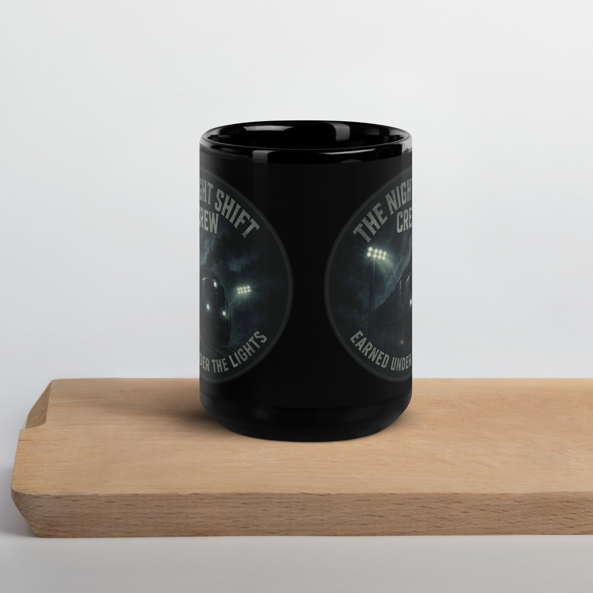 Black mug with graphic design and text on a wooden block against a white background