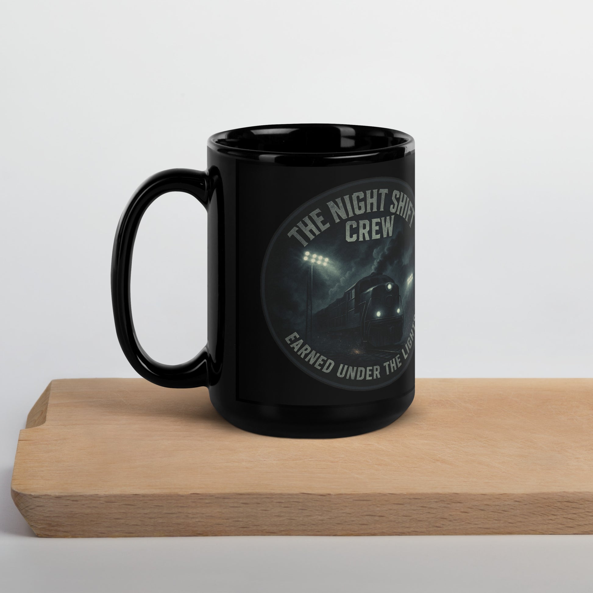 Black mug with 'The Night Shift Crew' design on a wooden block against a light background