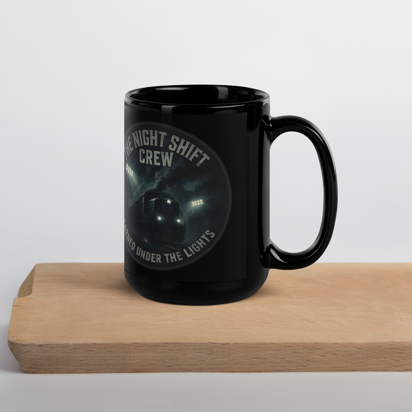 Black mug with 'Night Shift Crew' text on a wooden block against a white background