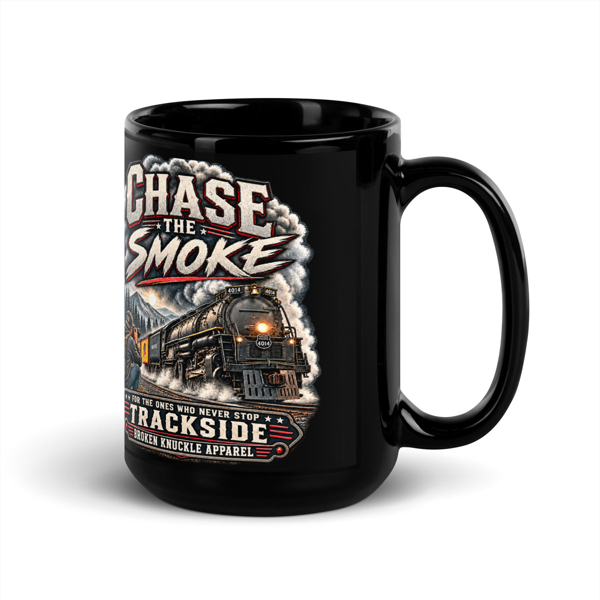 Black glossy 15 oz ceramic mug featuring a graphic of a photographer with a backpack kneeling trackside, taking a picture of a large steam locomotive. Bold distressed text reads "CHASE THE SMOKE" at the top and "FOR THE ONES WHO NEVER STOP TRACKSIDE" in a vintage banner at the bottom.