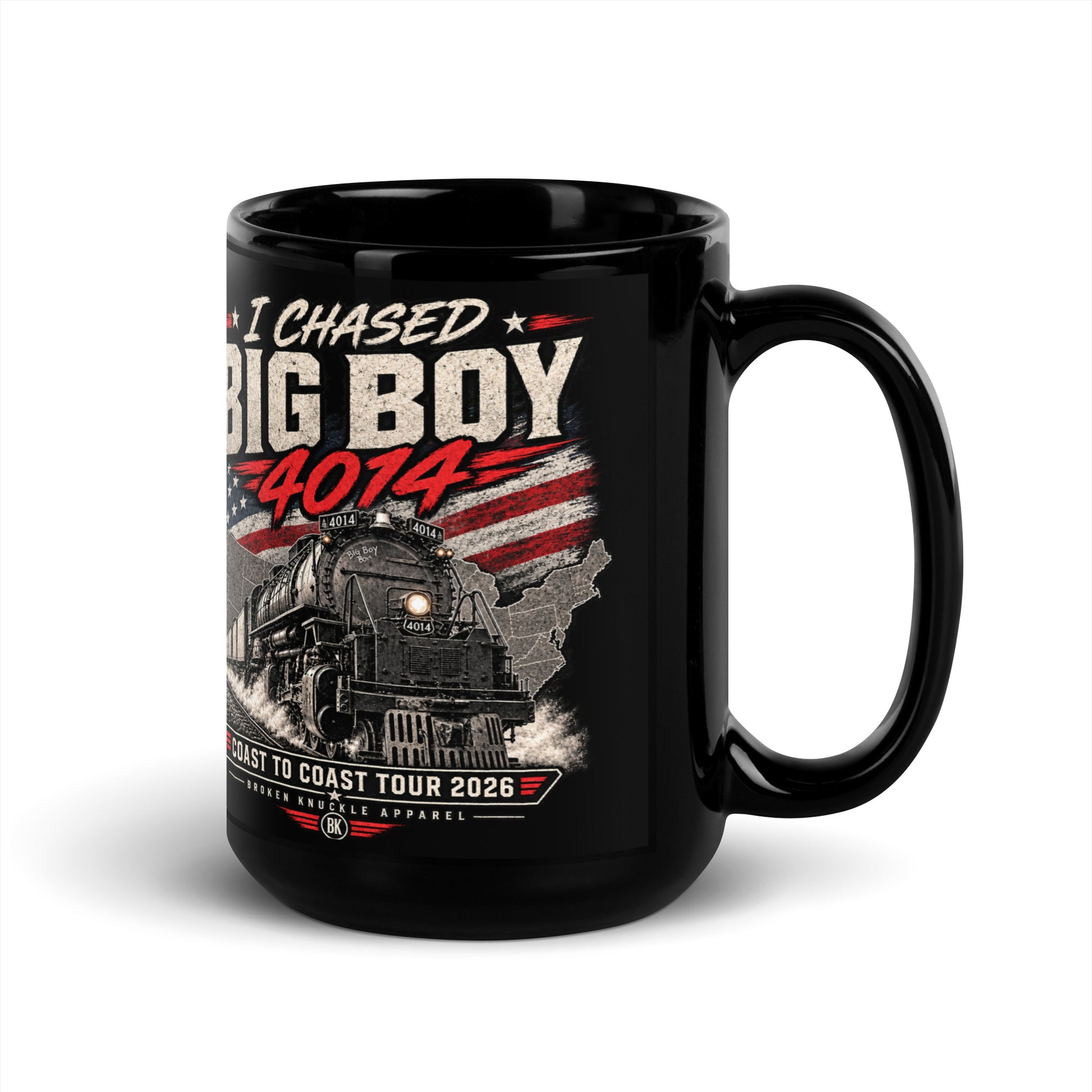 Black glossy 15 oz ceramic mug featuring a graphic of the Big Boy 4014 steam locomotive charging out of a USA map filled with the American flag. Distressed text reads "I CHASED BIG BOY 4014" at the top and "COAST TO COAST TOUR 2026" on a banner at the bottom above the Broken Knuckle Apparel logo.