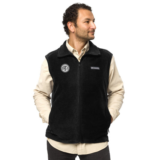Man wearing black Columbia fleece vest with embroidered DT&I Railroad logo, hands in pockets, looking to the side.