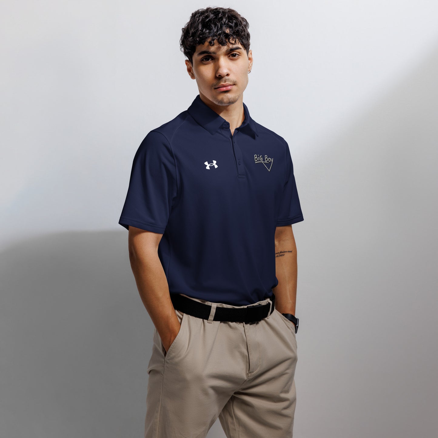 Navy Under Armour men's polo shirt featuring the classic white chalk-style "Big Boy" script logo on the left chest. A white Under Armour logo is displayed on the right chest. The shirt has a classic collar and a three-button placket.