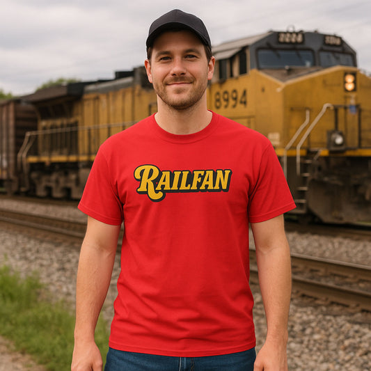 Man wearing a red 'RAILFAN' t-shirt standing in front of a train.