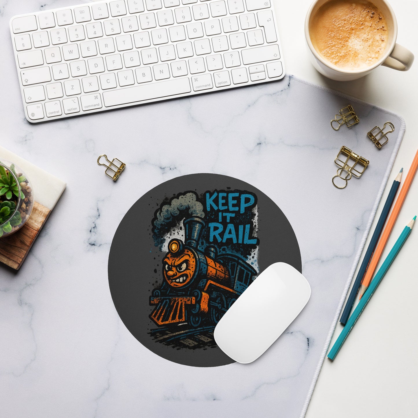 Mouse pad with train design and 'Keep It Rail' text on a marble desk with office supplies.