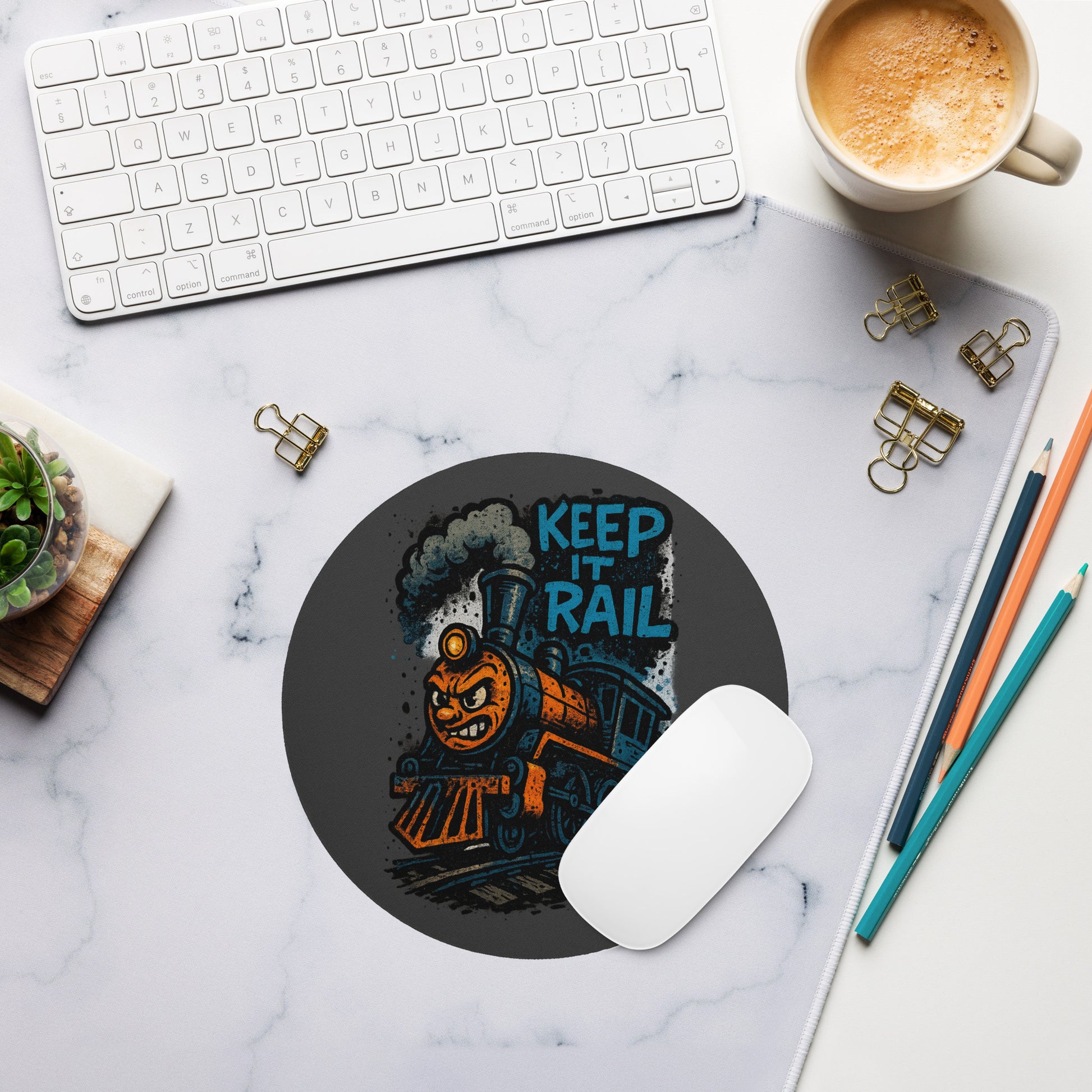 Mouse pad with train design and 'Keep It Rail' text on a marble desk with office supplies.