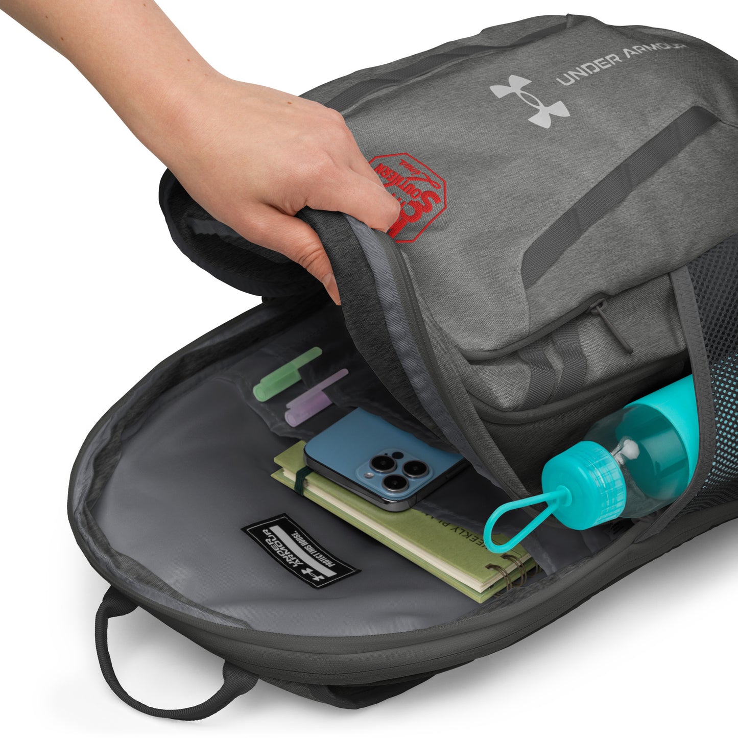 Gray Under Armour backpack with items inside on a white background