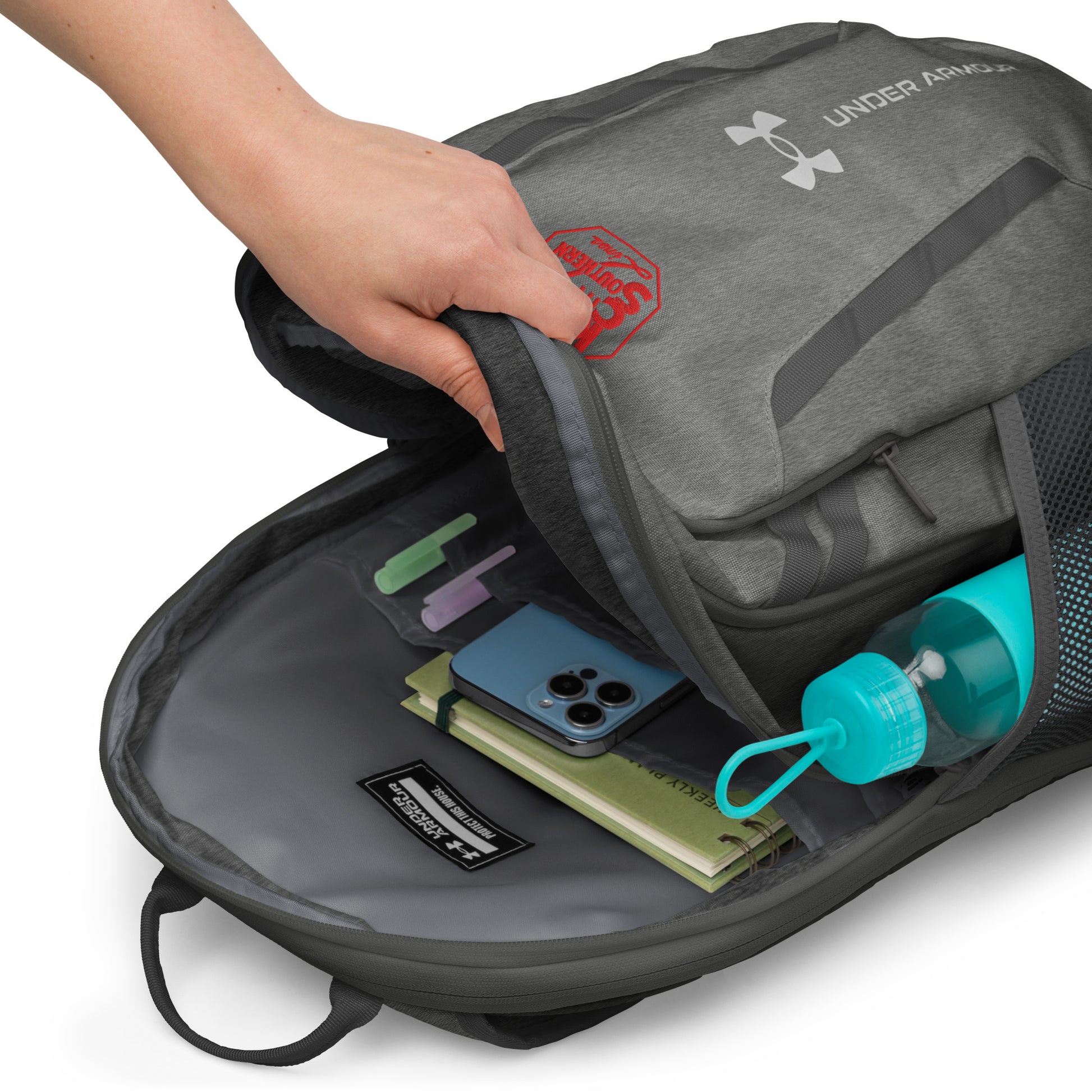 Gray Under Armour backpack with items inside on a white background