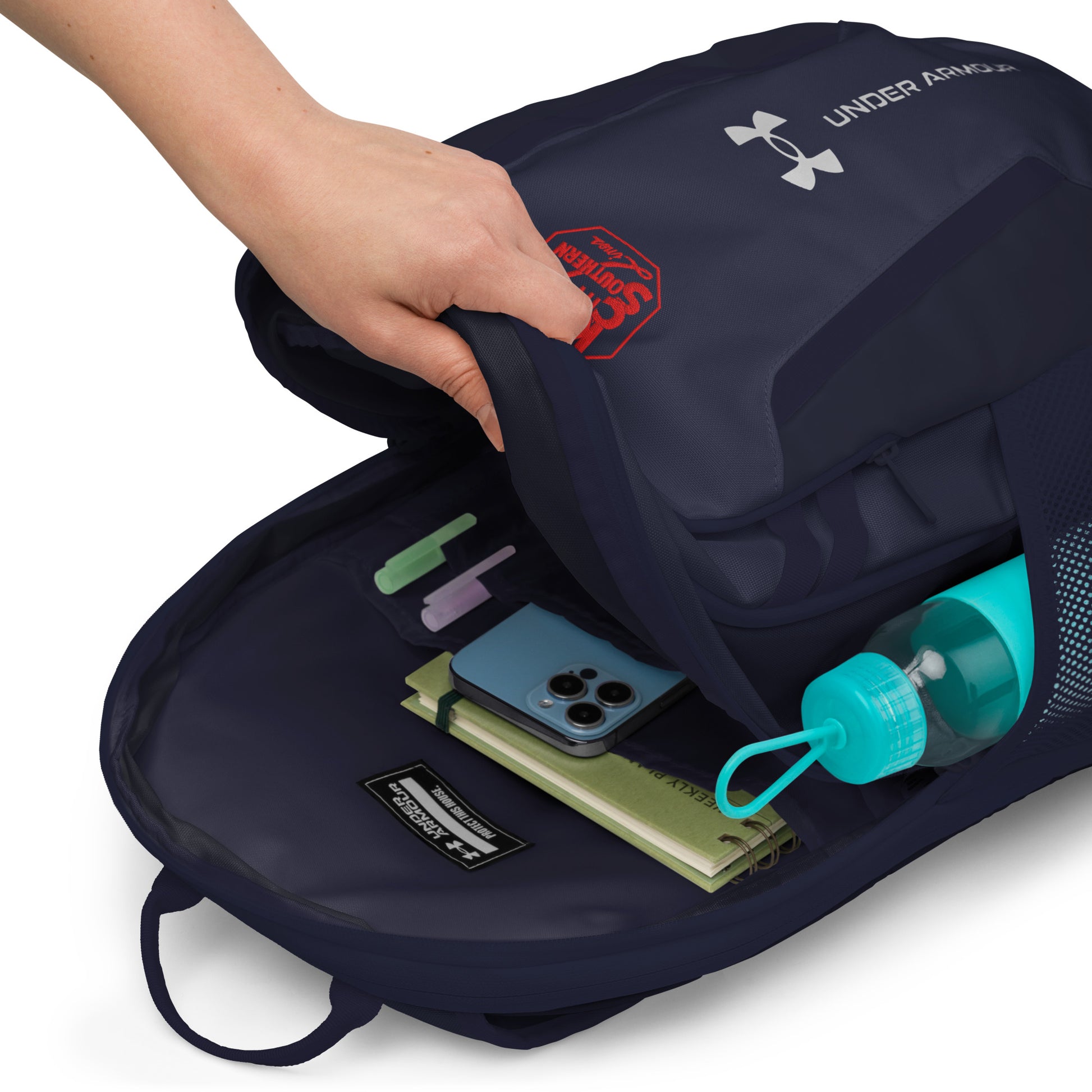 Navy Under Armour backpack with items like a phone and water bottle inside, on a white background