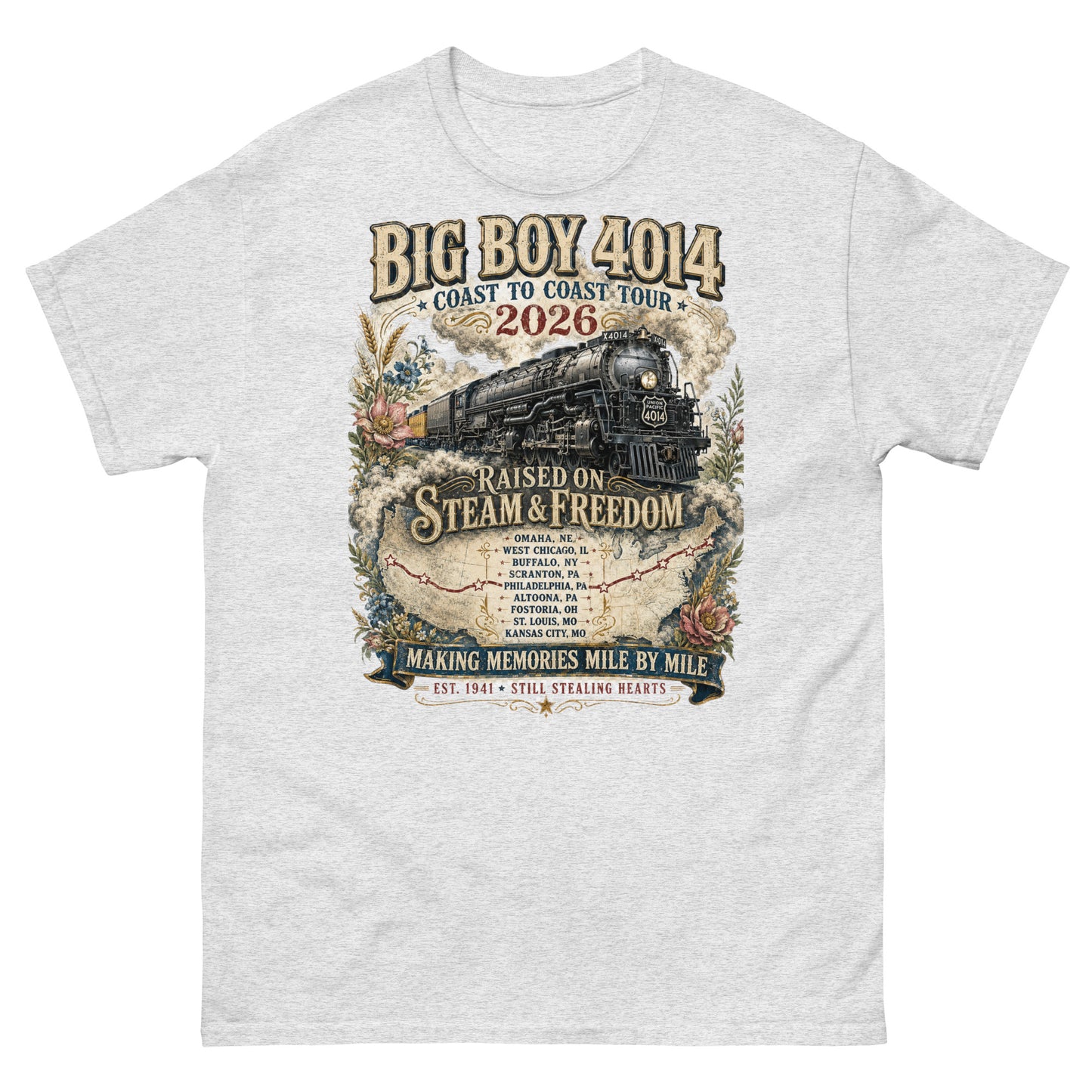 Ash colored t-shirt featuring a vintage graphic of the Big Boy 4014 steam locomotive. The train is surrounded by steam, classic floral designs, and a route map. Text reads "BIG BOY 4014", "COAST TO COAST TOUR 2026", and "RAISED ON STEAM & FREEDOM". Below is a roster of nine tour stops, anchored by banners reading "MAKING MEMORIES MILE BY MILE" and "EST. 1941 STILL STEALING HEARTS".
