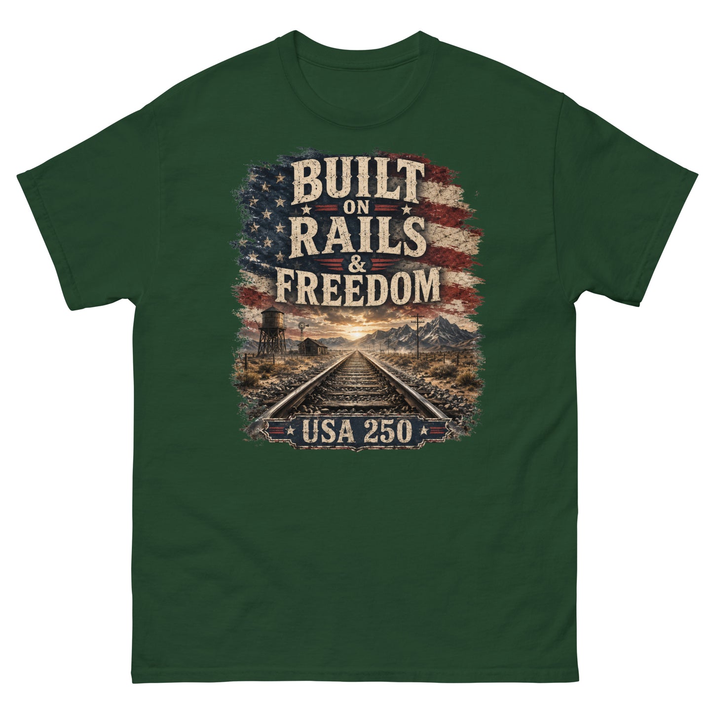 Forest green t-shirt featuring a distressed American flag graphic at the top with text reading "BUILT ON RAILS & FREEDOM". Below the text is a landscape illustration of railroad tracks leading toward mountains and a sunset, with a trackside water tower on the left. A banner at the bottom reads "USA 250".