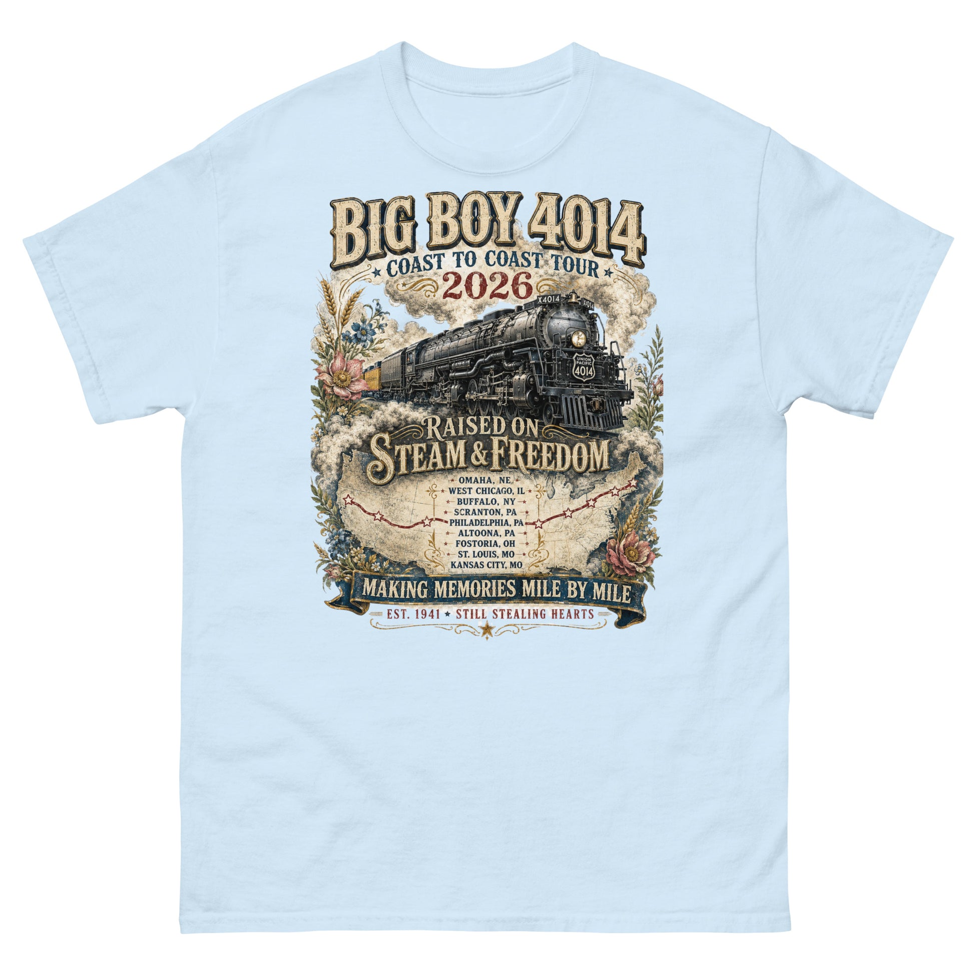 Light blue t-shirt featuring a vintage graphic of the Big Boy 4014 steam locomotive. The train is surrounded by steam, classic floral designs, and a route map. Text reads "BIG BOY 4014", "COAST TO COAST TOUR 2026", and "RAISED ON STEAM & FREEDOM". Below is a roster of nine tour stops, anchored by banners reading "MAKING MEMORIES MILE BY MILE" and "EST. 1941 STILL STEALING HEARTS".