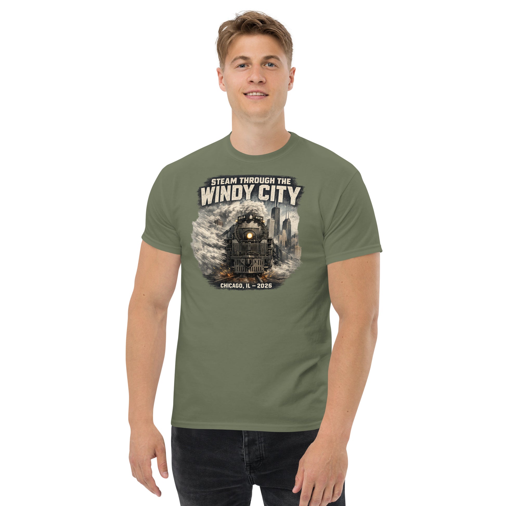 Army green t-shirt featuring a graphic of a steam locomotive emerging from smoke in front of a city skyline, with text reading "STEAM THROUGH THE WINDY CITY" at the top and "CHICAGO, IL - 2026" at the bottom.