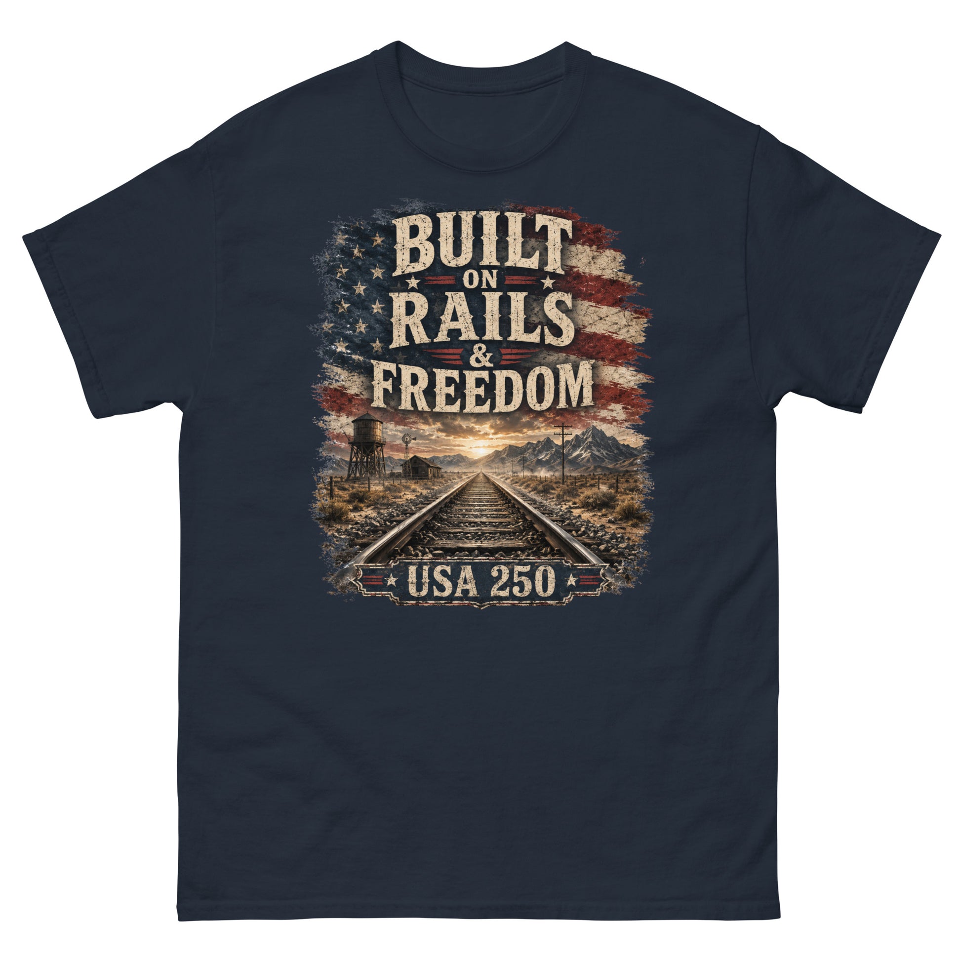 Navy t-shirt featuring a distressed American flag graphic at the top with text reading "BUILT ON RAILS & FREEDOM". Below the text is a landscape illustration of railroad tracks leading toward mountains and a sunset, with a trackside water tower on the left. A banner at the bottom reads "USA 250".