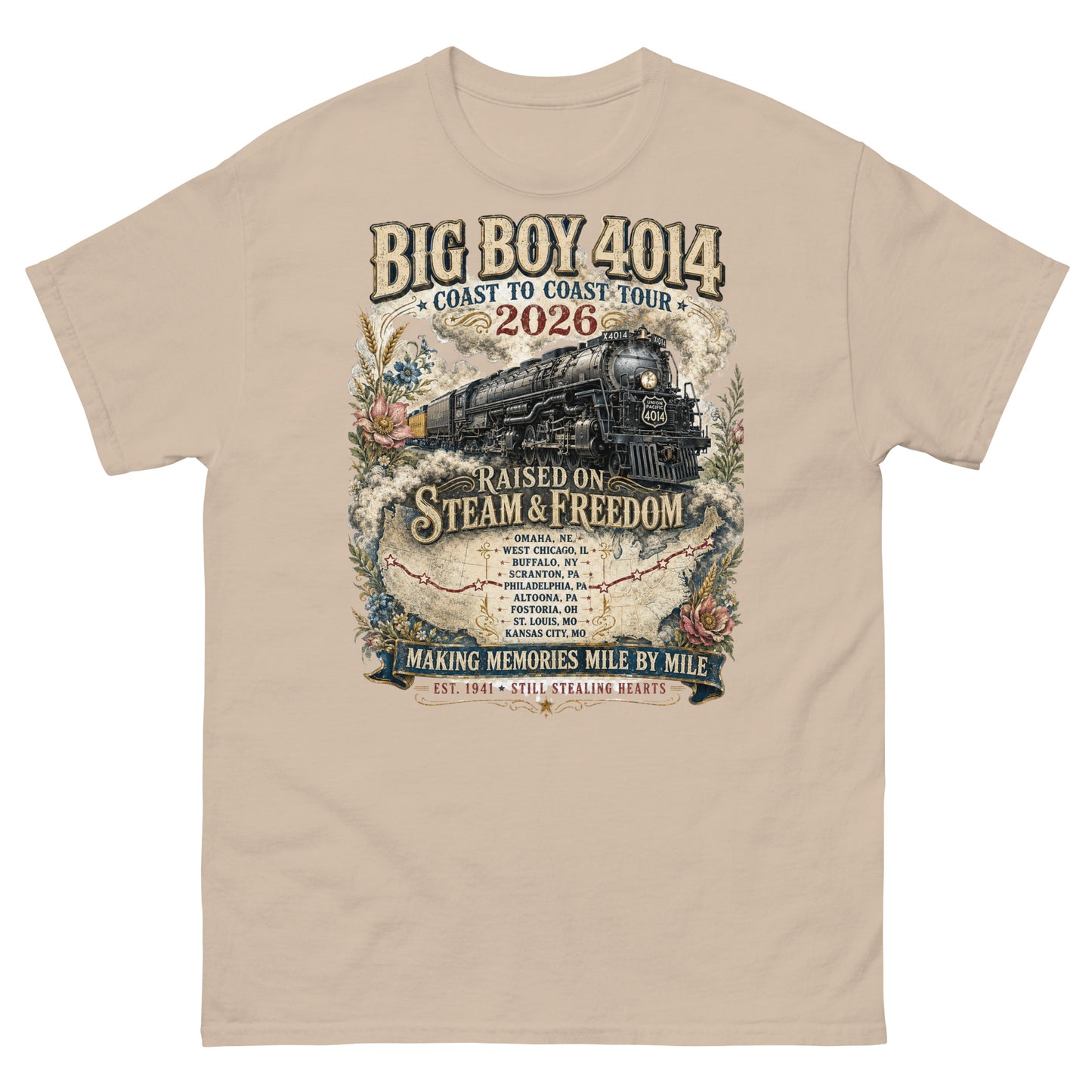 Sand-colored t-shirt featuring a vintage graphic of the Big Boy 4014 steam locomotive. The train is surrounded by steam, classic floral designs, and a route map. Text reads "BIG BOY 4014", "COAST TO COAST TOUR 2026", and "RAISED ON STEAM & FREEDOM". Below is a roster of nine tour stops, anchored by banners reading "MAKING MEMORIES MILE BY MILE" and "EST. 1941 STILL STEALING HEARTS".