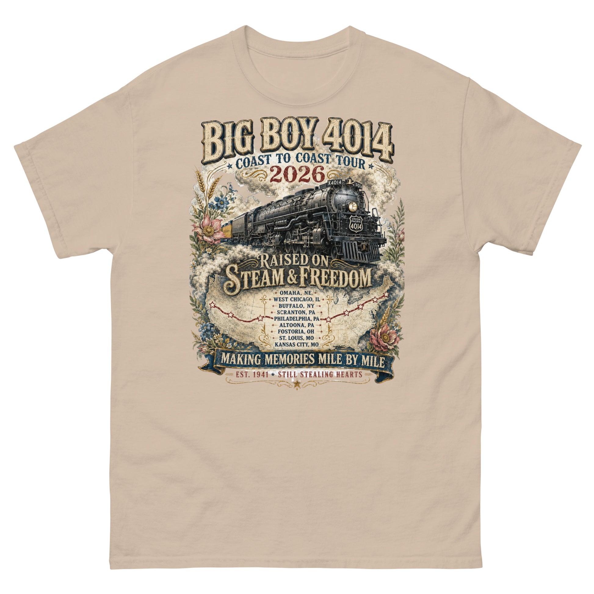 Sand-colored t-shirt featuring a vintage graphic of the Big Boy 4014 steam locomotive. The train is surrounded by steam, classic floral designs, and a route map. Text reads "BIG BOY 4014", "COAST TO COAST TOUR 2026", and "RAISED ON STEAM & FREEDOM". Below is a roster of nine tour stops, anchored by banners reading "MAKING MEMORIES MILE BY MILE" and "EST. 1941 STILL STEALING HEARTS".