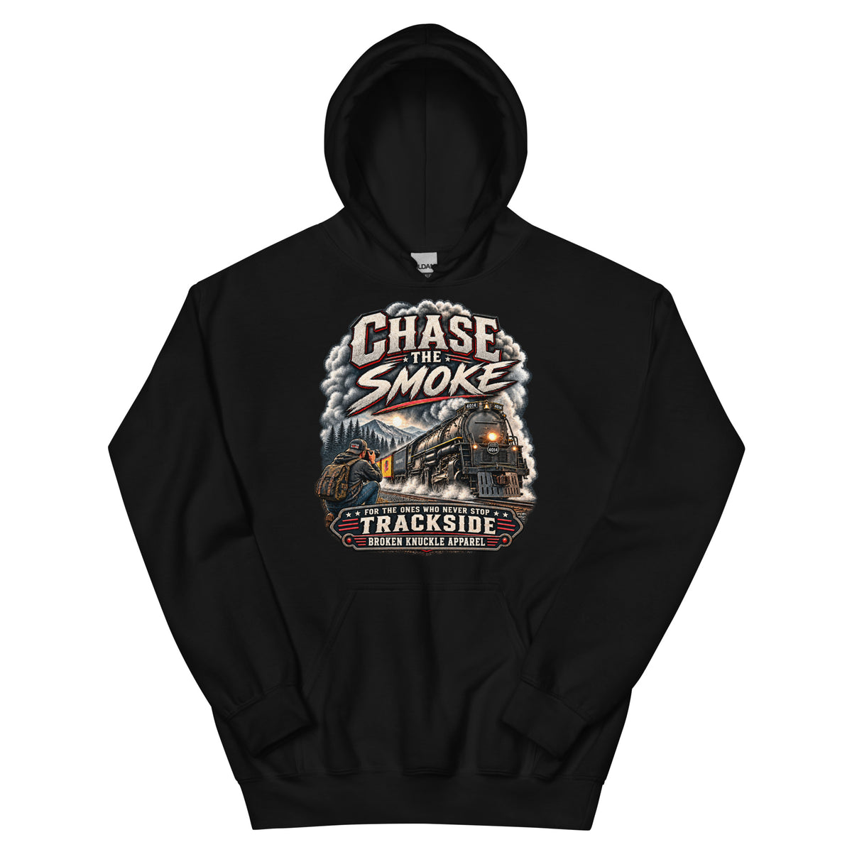 Black heavy blend pullover hoodie featuring a graphic of a photographer with a backpack kneeling trackside, taking a picture of a large steam locomotive rolling through a forest landscape. Bold distressed text reads "CHASE THE SMOKE" at the top and "FOR THE ONES WHO NEVER STOP TRACKSIDE" in a vintage banner at the bottom.