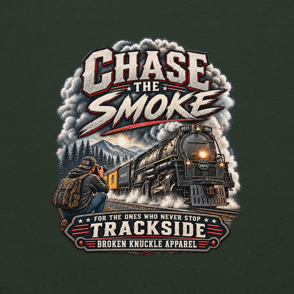Forest green heavy blend pullover hoodie featuring a graphic of a photographer with a backpack kneeling trackside, taking a picture of a large steam locomotive rolling through a forest landscape. Bold distressed text reads "CHASE THE SMOKE" at the top and "FOR THE ONES WHO NEVER STOP TRACKSIDE" in a vintage banner at the bottom.