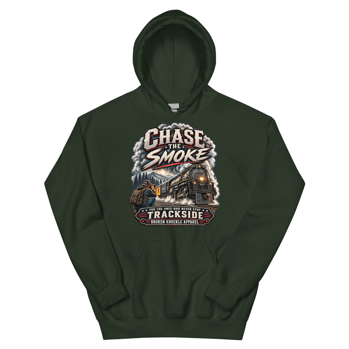 Forest green heavy blend pullover hoodie featuring a graphic of a photographer with a backpack kneeling trackside, taking a picture of a large steam locomotive rolling through a forest landscape. Bold distressed text reads "CHASE THE SMOKE" at the top and "FOR THE ONES WHO NEVER STOP TRACKSIDE" in a vintage banner at the bottom.