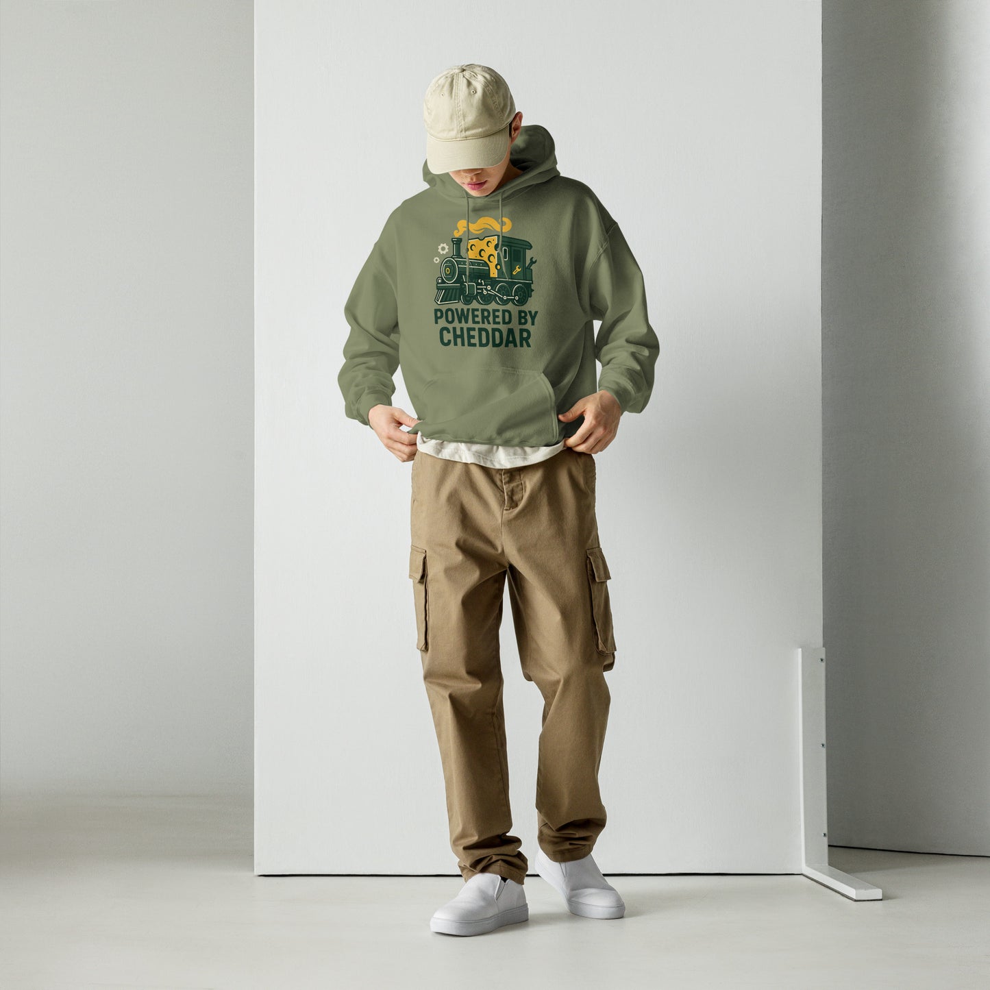 Person wearing a green hoodie with text and graphics, brown cargo pants, and white shoes on a plain background