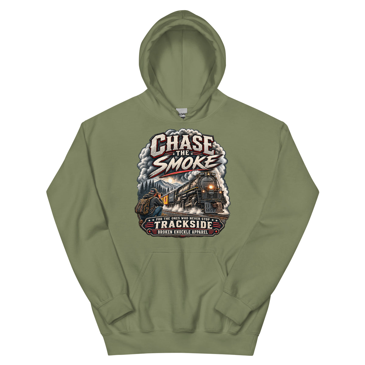 Army green heavy blend pullover hoodie featuring a graphic of a photographer with a backpack kneeling trackside, taking a picture of a large steam locomotive rolling through a forest landscape. Bold distressed text reads "CHASE THE SMOKE" at the top and "FOR THE ONES WHO NEVER STOP TRACKSIDE" in a vintage banner at the bottom.