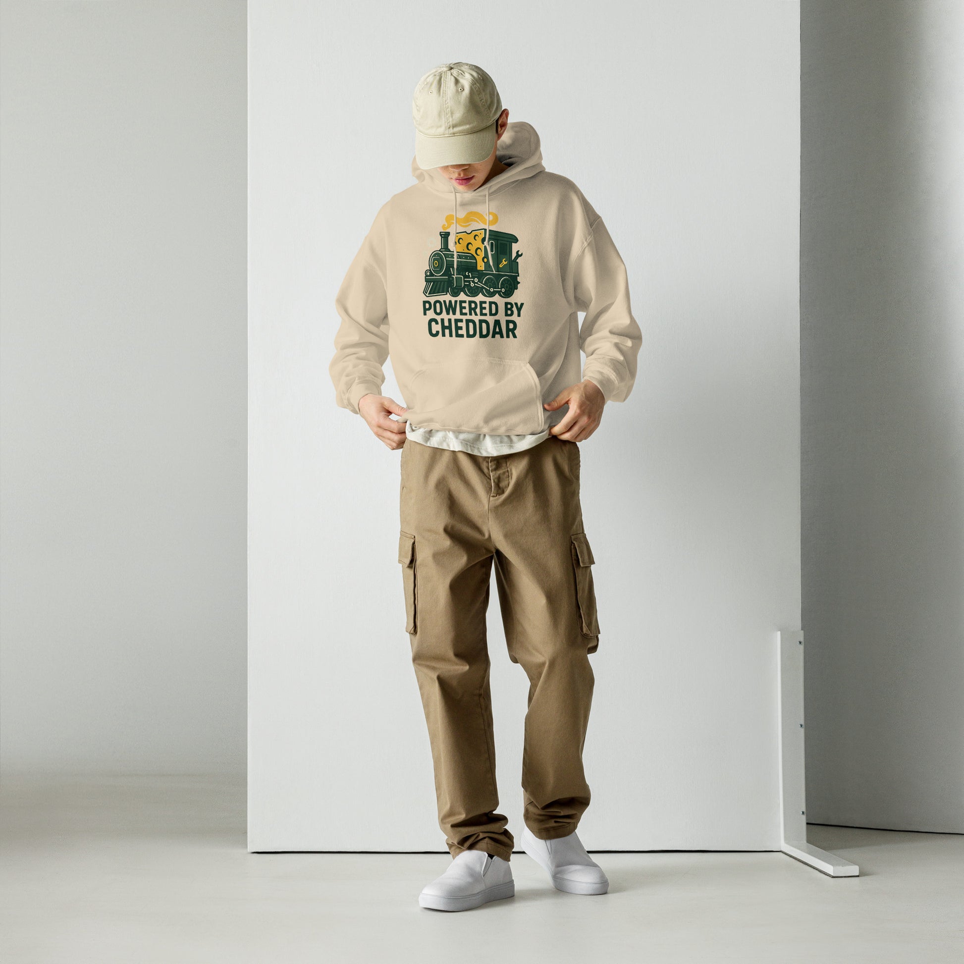 Person wearing a beige hoodie with text and graphics, brown cargo pants, and white sneakers on a plain background