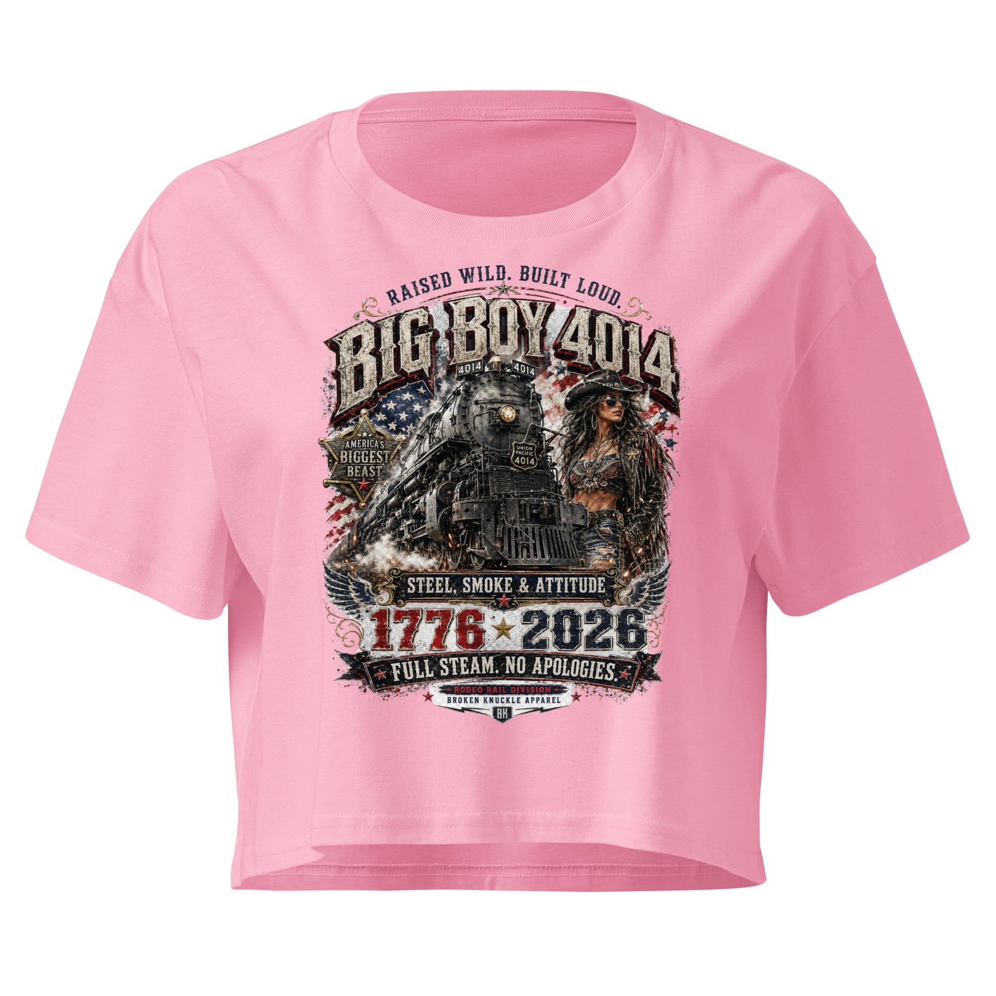 Pink women's crop top featuring a gritty graphic of the Big Boy 4014 steam locomotive next to a woman in a cowboy hat and leather jacket. The background includes a distressed American flag and eagle wings. Text reads "RAISED WILD. BUILT LOUD.", "BIG BOY 4014", "AMERICA'S BIGGEST BEAST", "STEEL, SMOKE & ATTITUDE", "1776 - 2026", "FULL STEAM. NO APOLOGIES.", and "RODEO RAIL DIVISION".