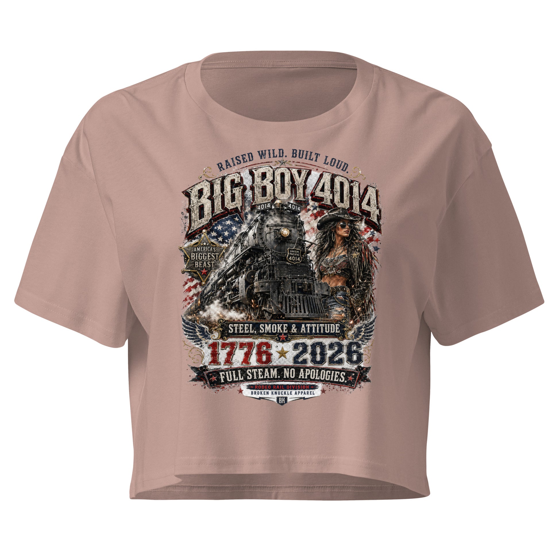 Beige women's crop top featuring a gritty graphic of the Big Boy 4014 steam locomotive next to a woman in a cowboy hat and leather jacket. The background includes a distressed American flag and eagle wings. Text reads "RAISED WILD. BUILT LOUD.", "BIG BOY 4014", "AMERICA'S BIGGEST BEAST", "STEEL, SMOKE & ATTITUDE", "1776 - 2026", "FULL STEAM. NO APOLOGIES.", and "RODEO RAIL DIVISION".