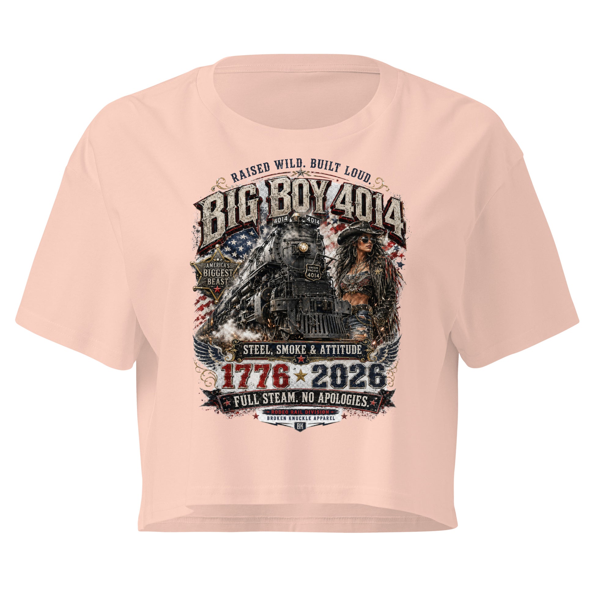 Light Pink women's crop top featuring a gritty graphic of the Big Boy 4014 steam locomotive next to a woman in a cowboy hat and leather jacket. The background includes a distressed American flag and eagle wings. Text reads "RAISED WILD. BUILT LOUD.", "BIG BOY 4014", "AMERICA'S BIGGEST BEAST", "STEEL, SMOKE & ATTITUDE", "1776 - 2026", "FULL STEAM. NO APOLOGIES.", and "RODEO RAIL DIVISION".