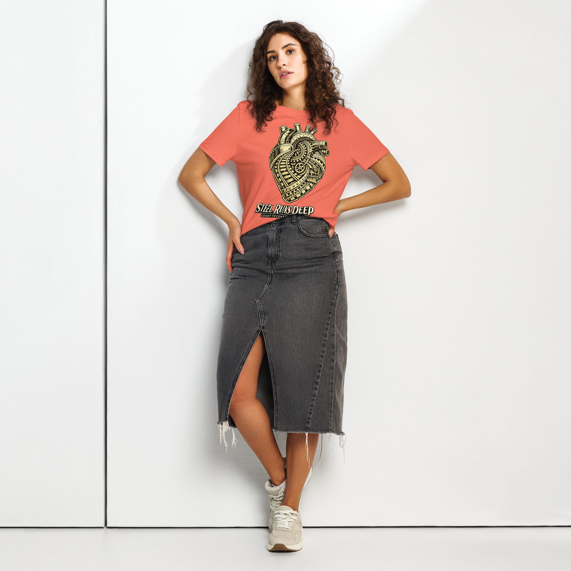 Orange women's t-shirt featuring an intricate vintage illustration of a mechanical heart made of train tracks and gears, with text reading "Steel Runs Deep" and "Coast to Coast 2026".