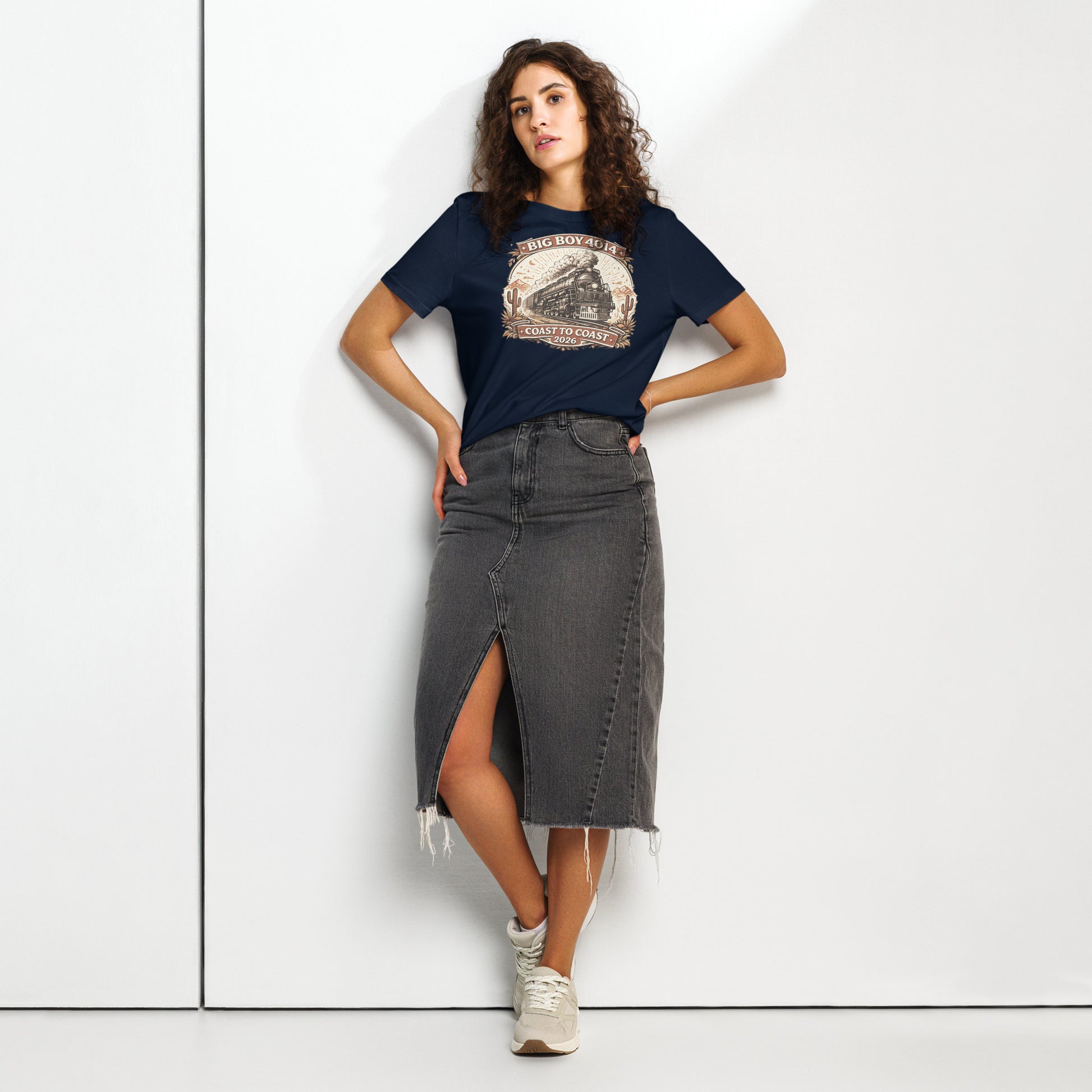 Woman wearing a navy t-shirt with a graphic design and a gray denim skirt on a white background