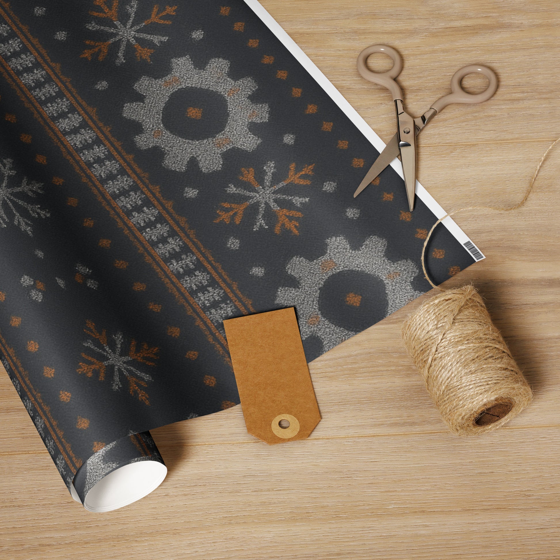 Roll of decorative paper with snowflake pattern, scissors, and twine on a wooden surface