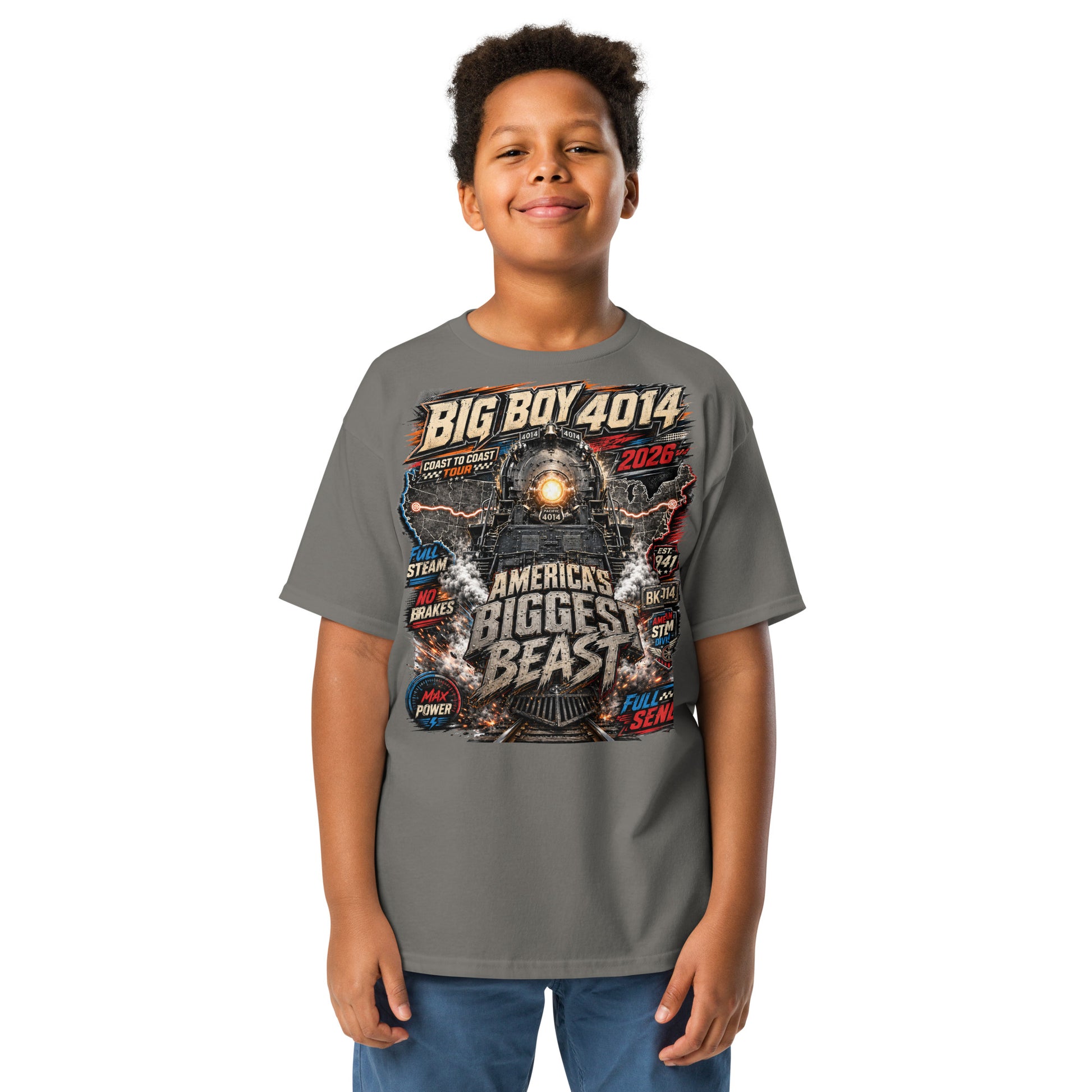 Child wearing a gray t-shirt featuring a high-energy, colorful graphic of the Big Boy 4014 steam locomotive backed by a US map, with bold text reading "BIG BOY 4014", "COAST TO COAST TOUR 2026", "AMERICA'S BIGGEST BEAST", "FULL STEAM", "NO BRAKES", "MAX POWER", and "FULL SEND".