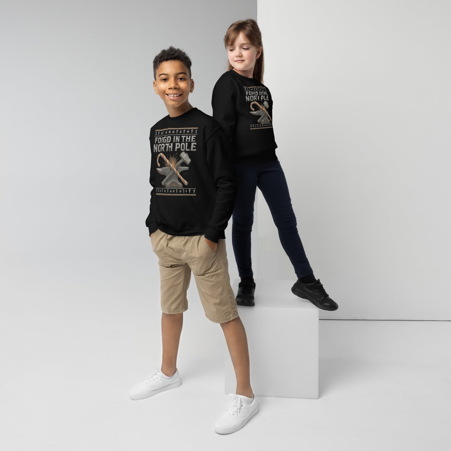 Two children wearing black sweatshirts with text and graphics on a white background