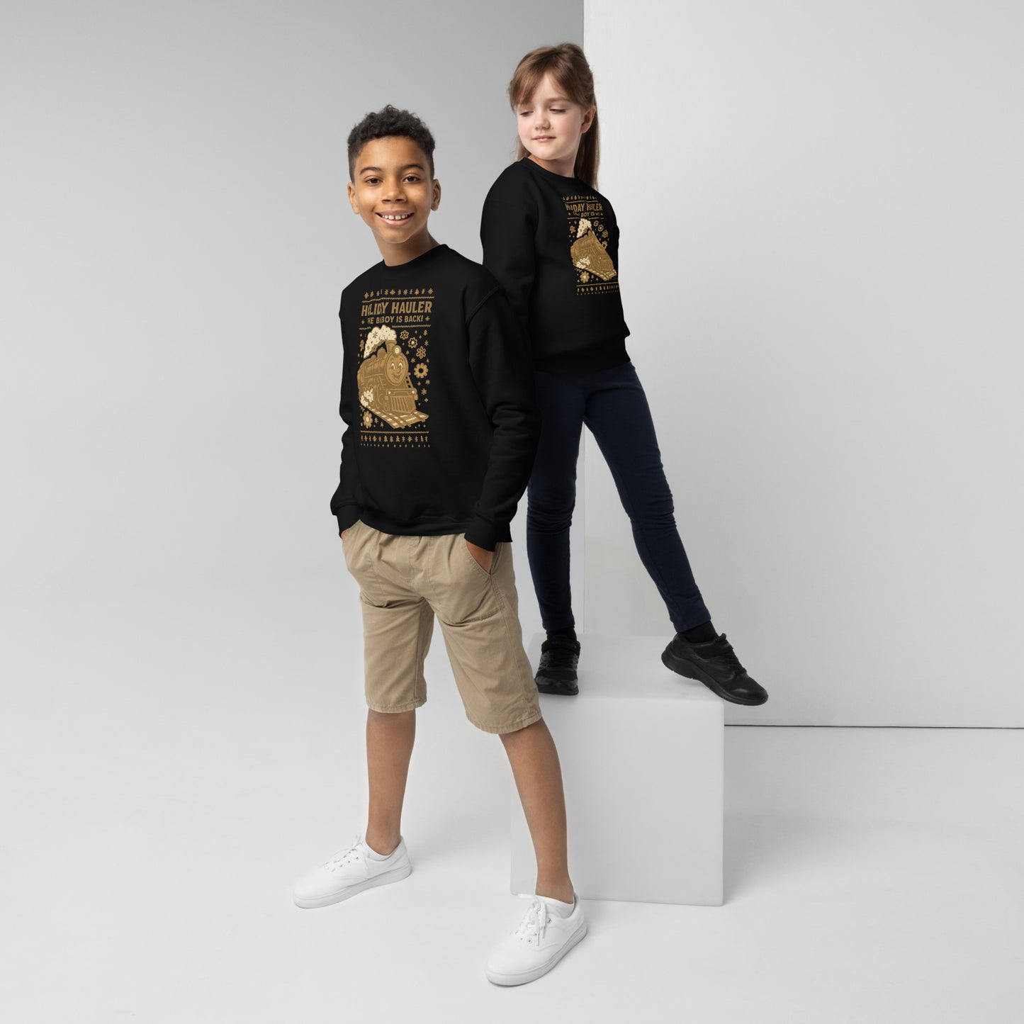 Two children wearing black sweatshirts with gold designs on a white background