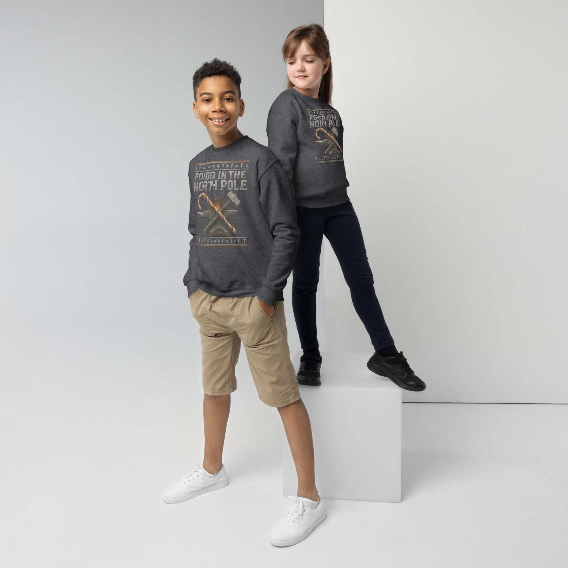 Two children wearing matching dark gray sweatshirts on a white background