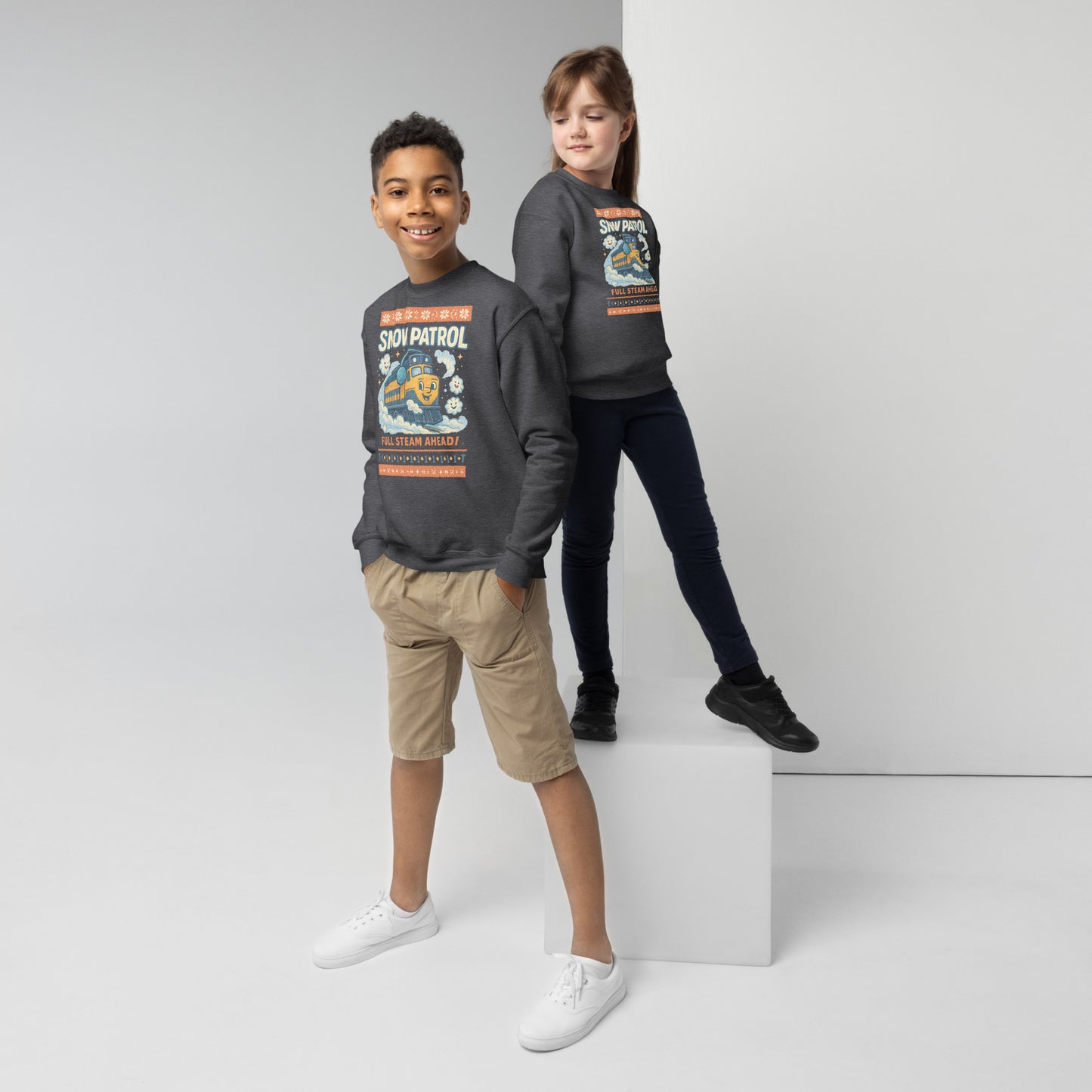 Two children wearing matching gray sweatshirts with a design on a white background