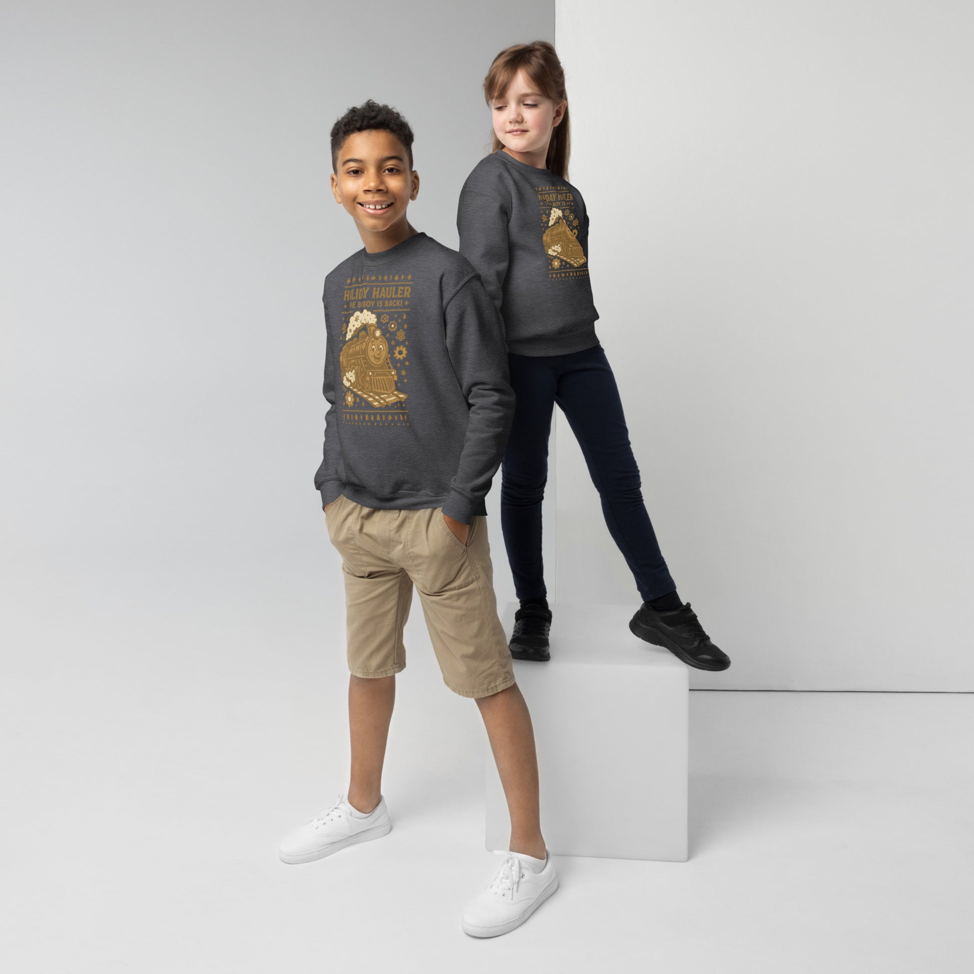Two children wearing matching gray sweatshirts with a graphic design on a white background