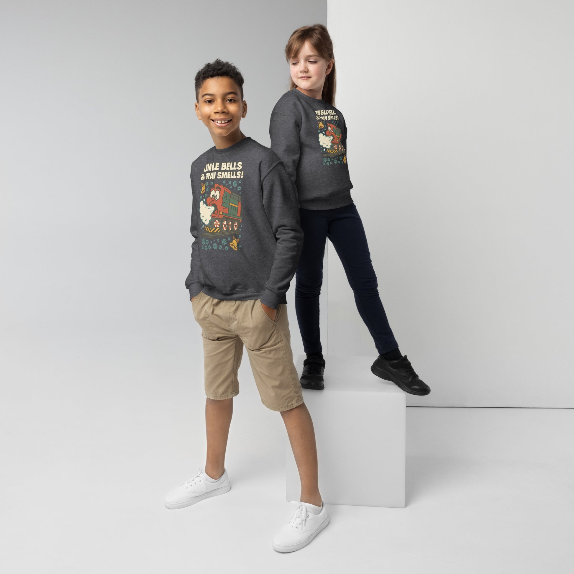 Two children wearing matching dark gray sweatshirts with festive designs on a white background.