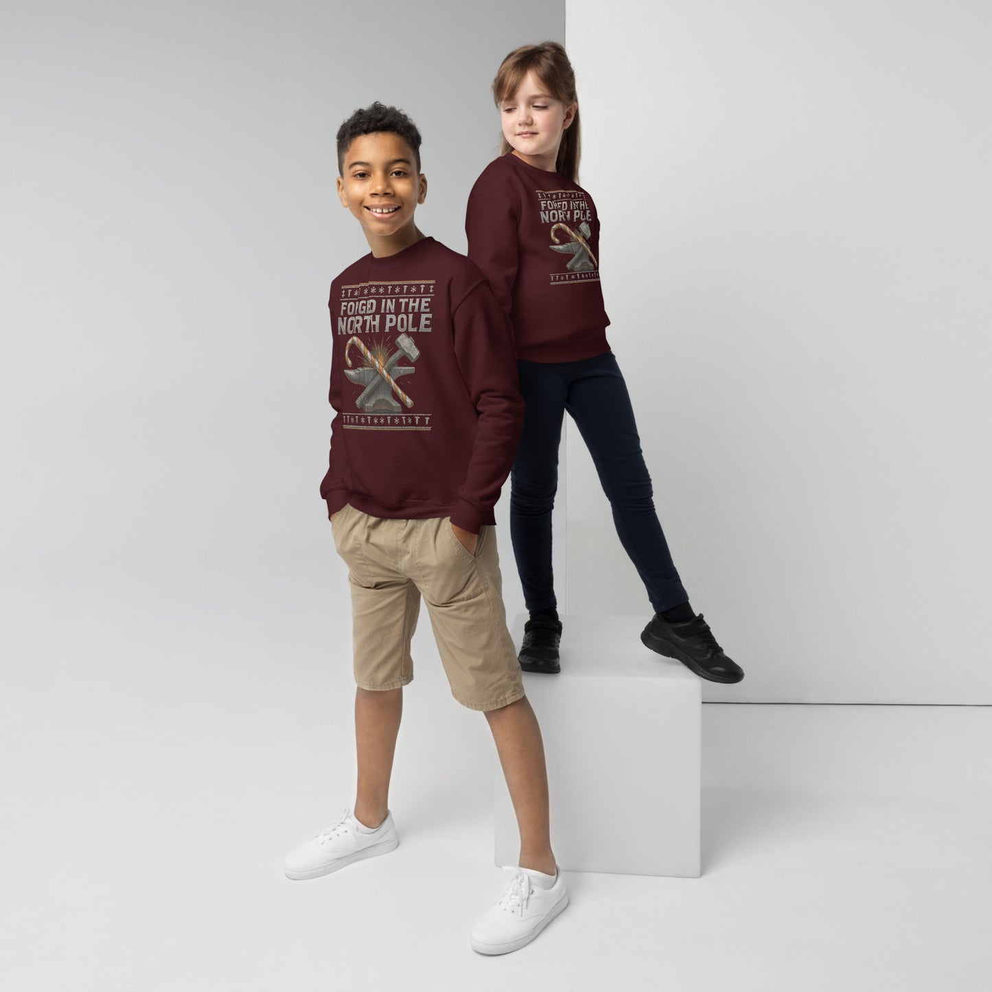 Two children wearing matching maroon sweatshirts on a white background