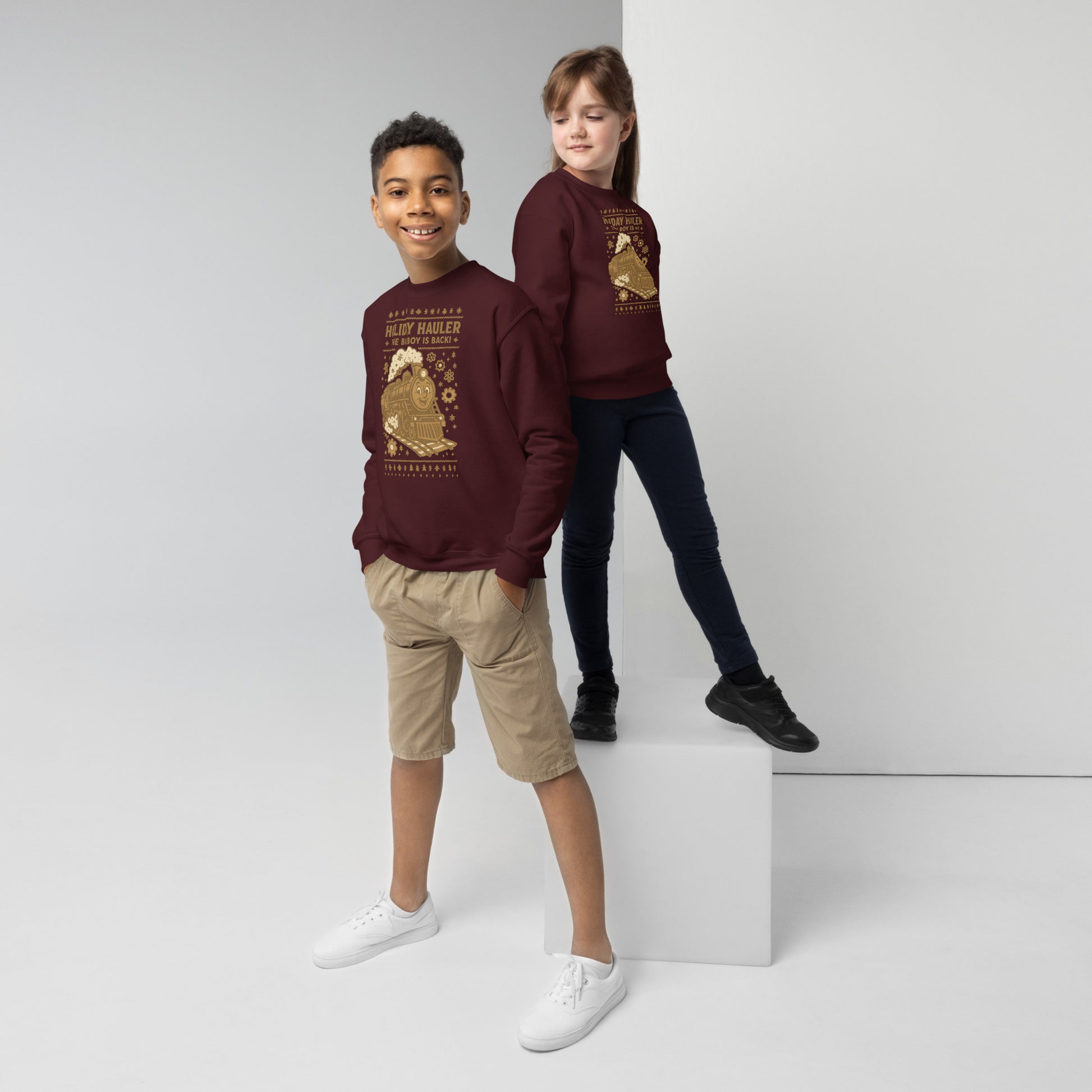 Two children wearing matching maroon sweatshirts with a design on a white background