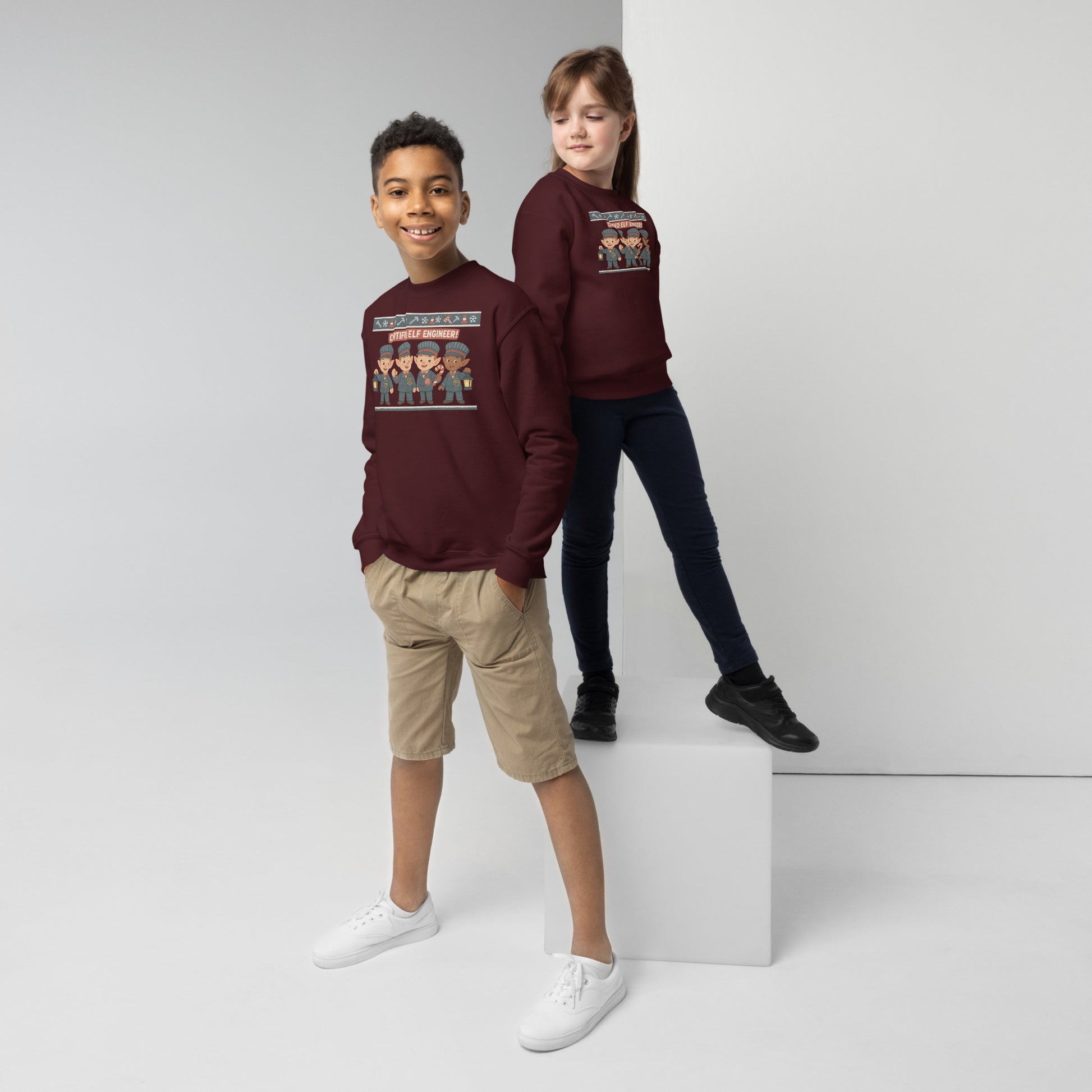 Two children wearing matching maroon sweatshirts on a white background