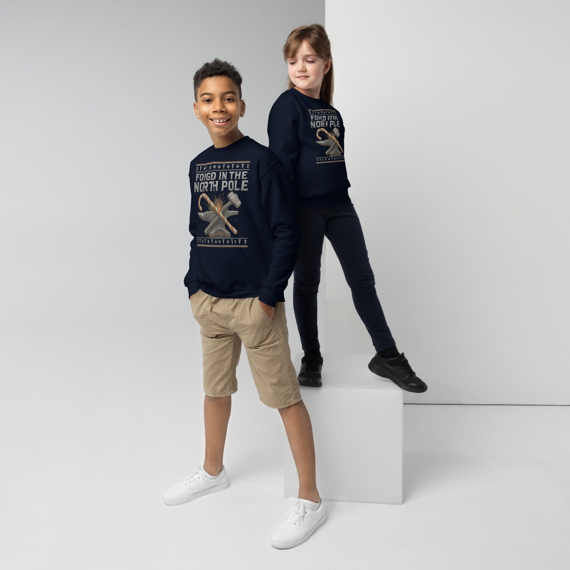 Two children wearing navy blue sweatshirts with text and graphics on a white background