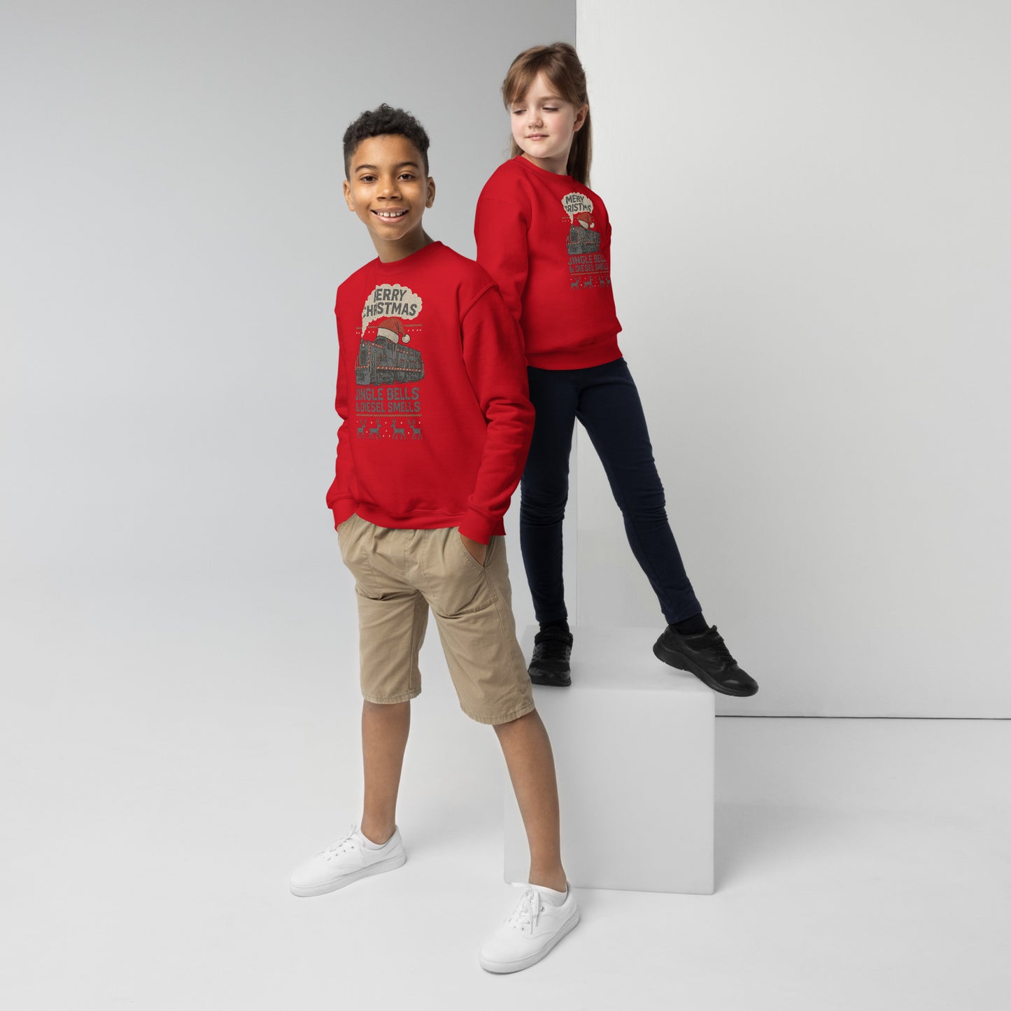 Two children wearing red sweatshirts standing on a white platform against a light gray background